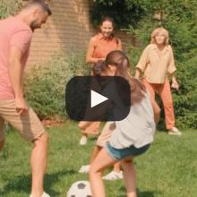 Photo of family playing soccer in garden