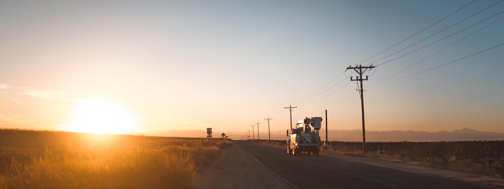 Truck driving down road in sunrise