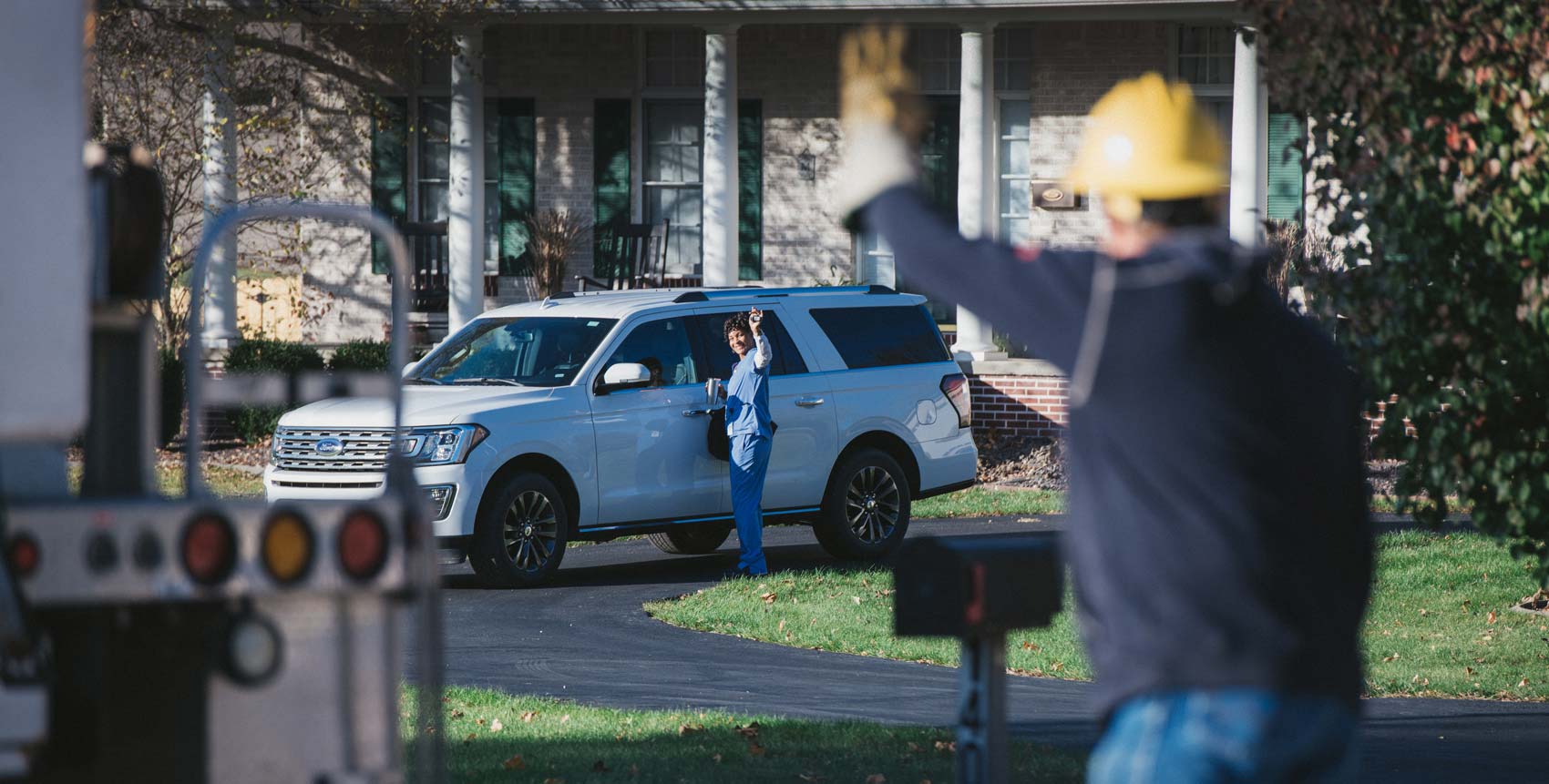 Co-op employee waving at member in driveway