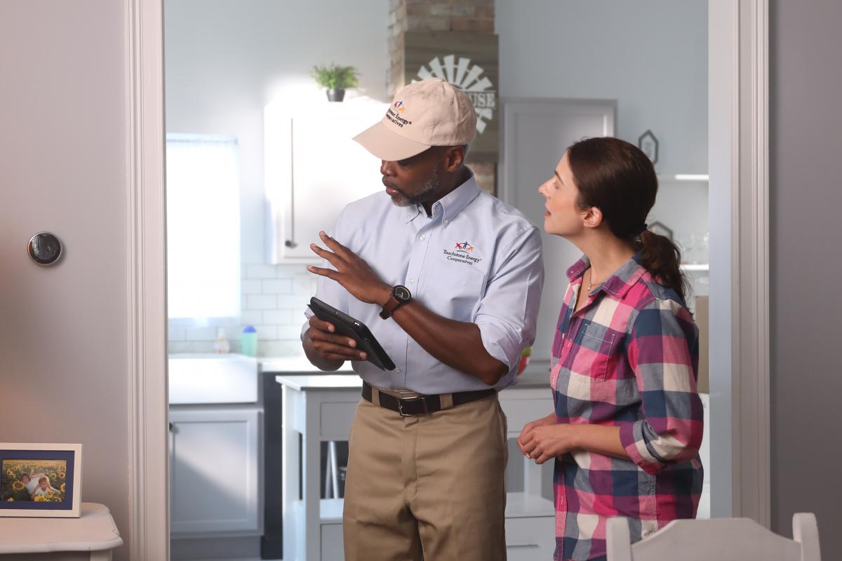 Co-op employee with homeowner and smart thermostat
