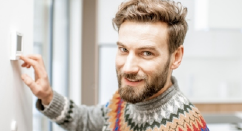 Man smiling and adjusting thermostat
