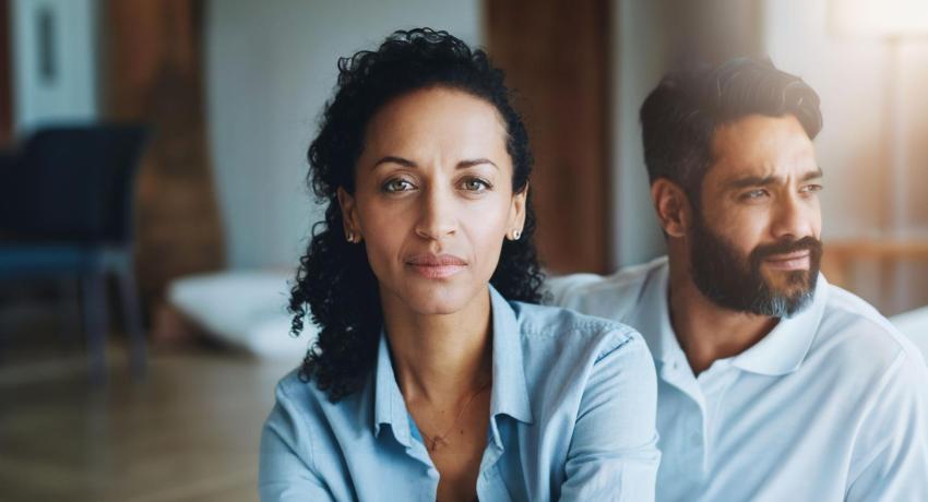 Photo of woman looking at camera, man sitting behind her looking away