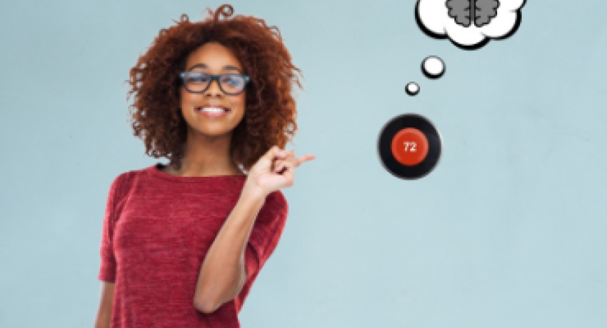 Photo of woman smiling and pointing to smart thermostat