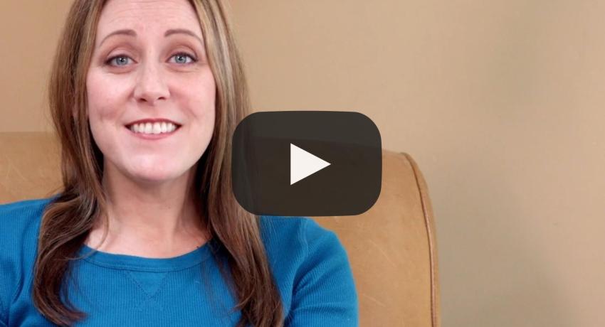 Woman sitting on sofa looking into camera smiling