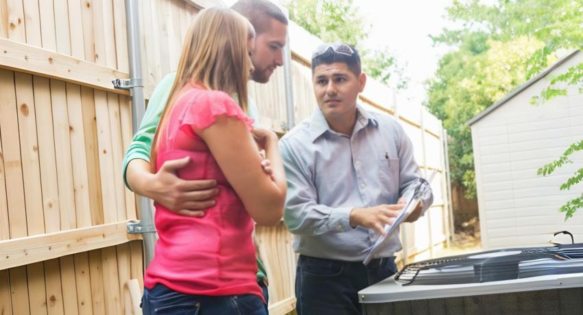 members in back yard looking at air conditioner with technician