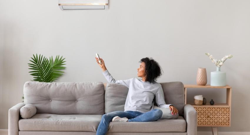 Photo of woman sitting on sofa, holding remote control