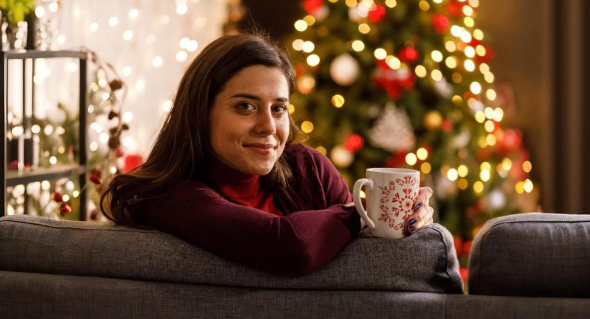 Woman sitting on sofa in front of a Christmas tree