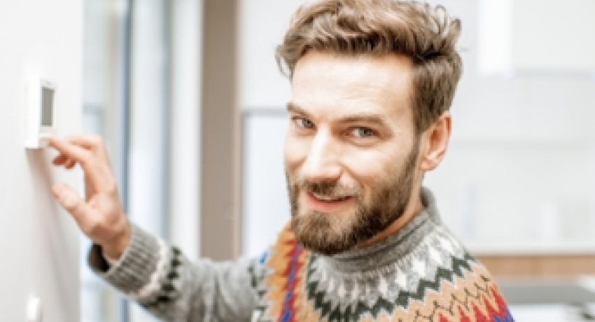 Man smiling and adjusting thermostat