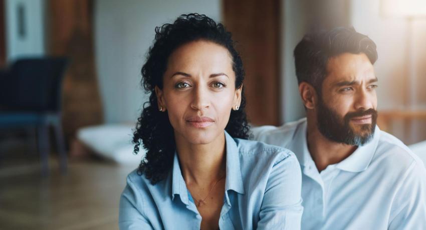 Photo of woman looking at camera, man sitting behind her looking away