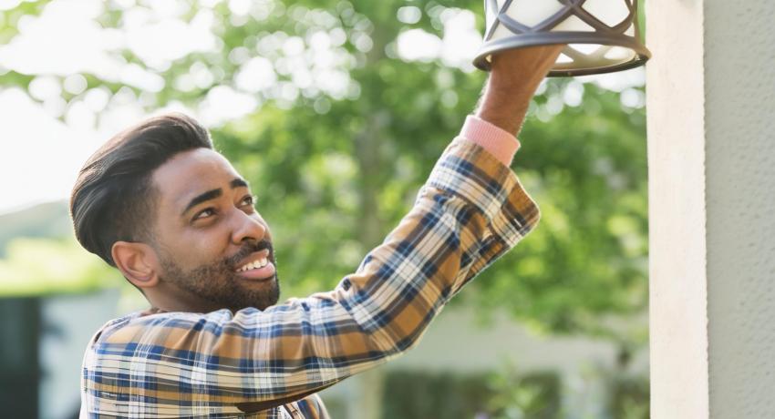 Photo of man changing outdoor light bulb 