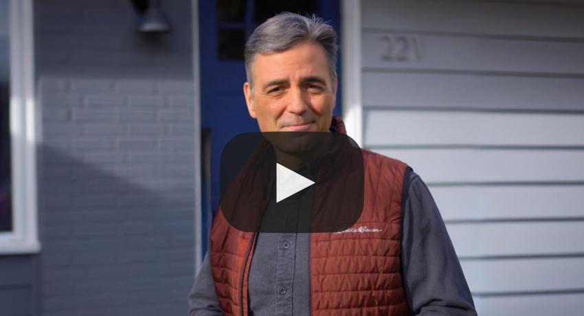 Man outside home with play button for video