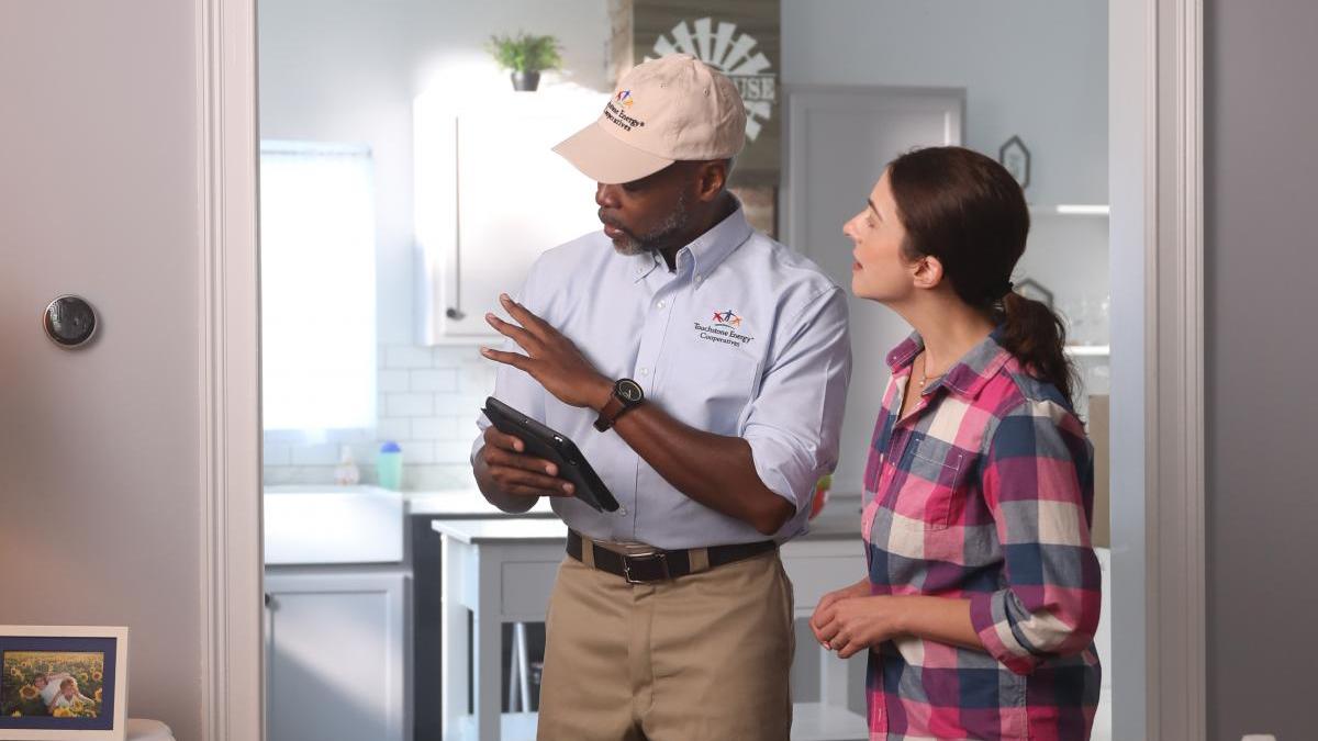 Co-op employee with homeowner and smart thermostat
