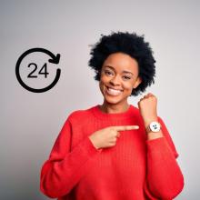 Woman pointing to her wrist watch; watch face says 24.
