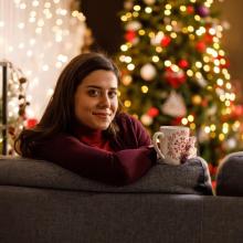 Woman sitting on sofa in front of a Christmas tree