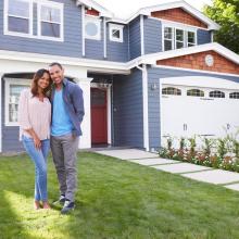 Photo of man and woman standing on lawn in front of a house