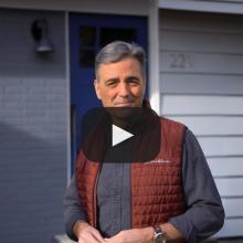 Man outside home with play button for video